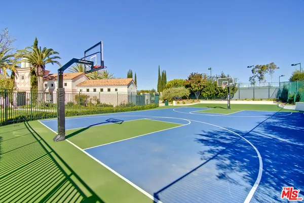 a view of a tennis ground with large trees