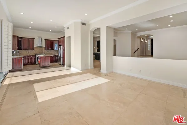 a living room with stainless steel appliances furniture and a kitchen view