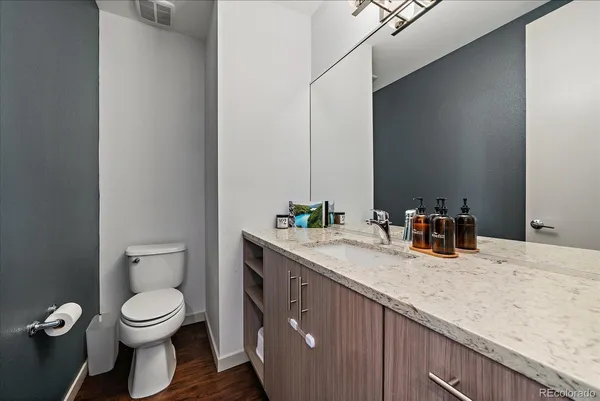 a bathroom with a granite countertop toilet a sink and a mirror