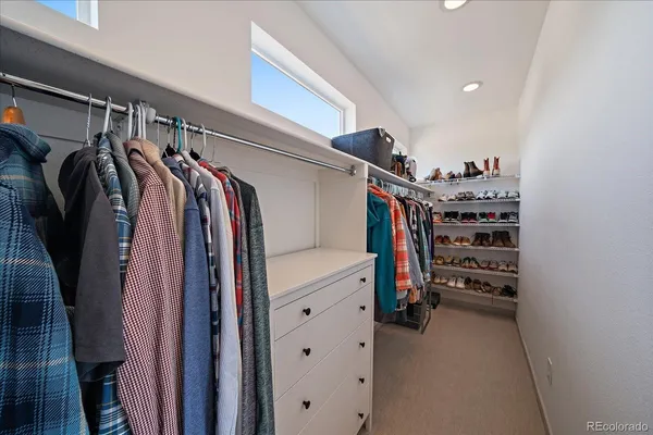 a view of walk in closet with clothes and shoes