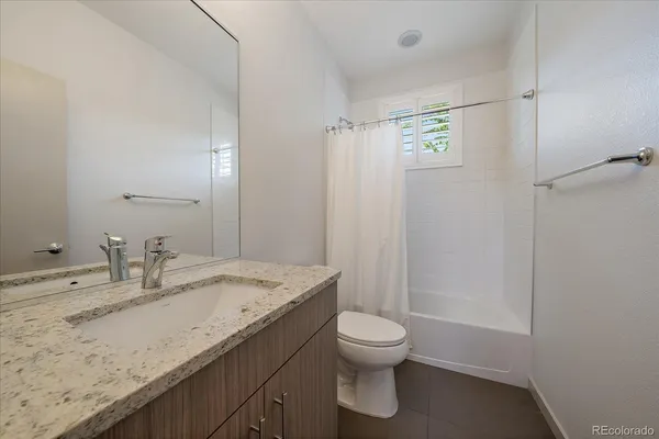a bathroom with a granite countertop sink a toilet and a shower