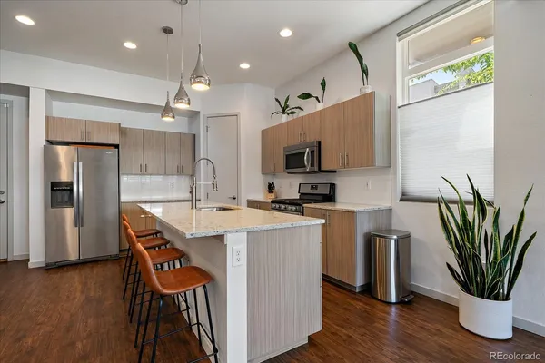 a kitchen with stainless steel appliances a microwave a sink a stove a refrigerator cabinets and wooden floor