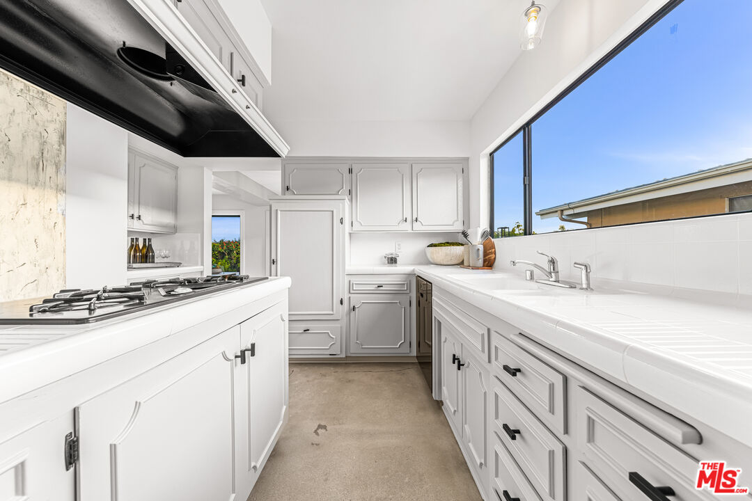18440 Wakecrest Drive Malibu, CA 90265 - Photo 12 of 29 a kitchen with white cabinets sink and stove