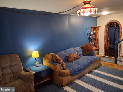 a living room with furniture a flat screen tv and a lamp