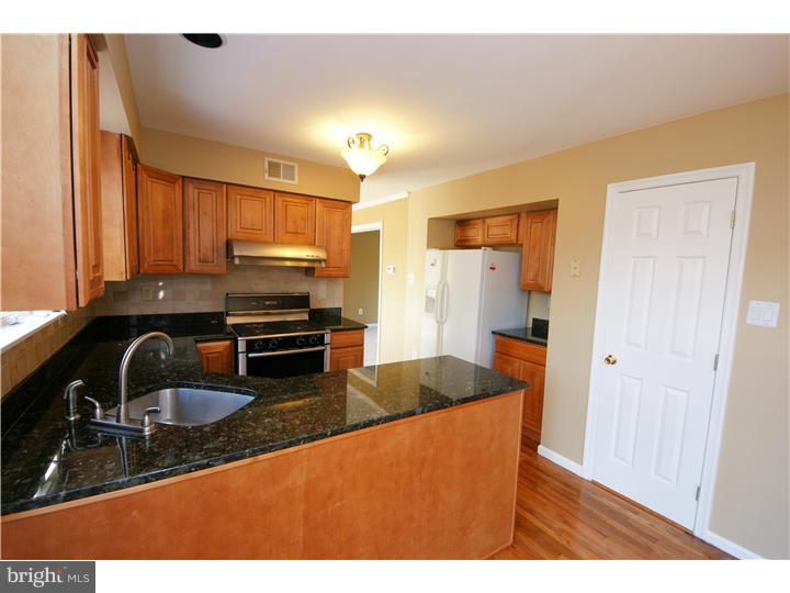 71 Amberfield Road Robbinsville, NJ 08691 - Photo 6 of 25 a kitchen with granite countertop a sink and a stove top oven with wooden floor