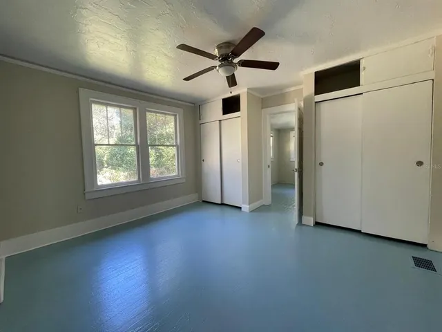 an empty room with ceiling fan and window