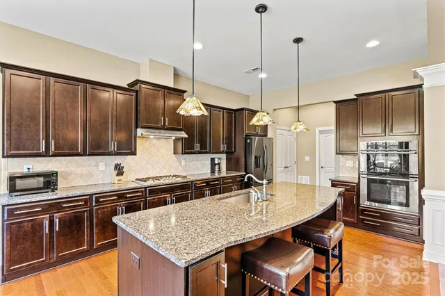 a kitchen with stainless steel appliances granite countertop a sink refrigerator and cabinets