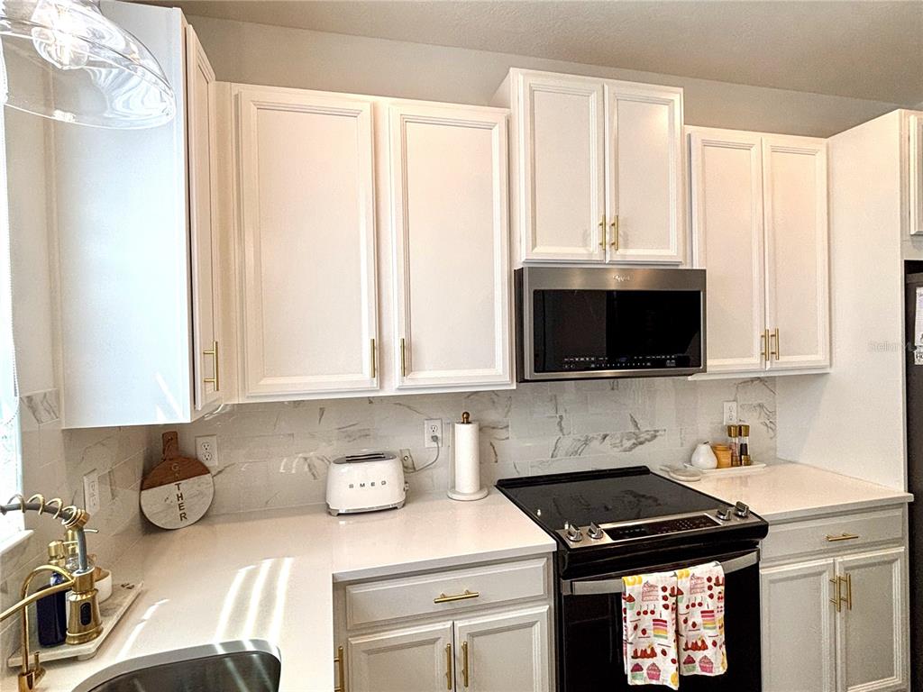 921 Spring Palms Loop Orlando, FL 32828 - Photo 19 of 43 a kitchen with stainless steel appliances a stove a sink and a microwave