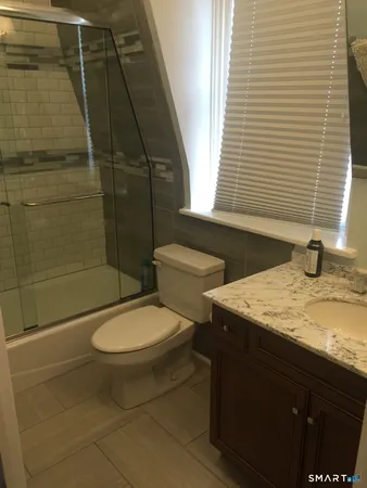 a bathroom with a granite countertop toilet a sink and shower