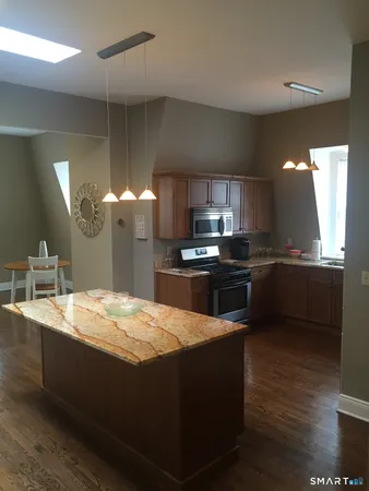 a kitchen with stainless steel appliances kitchen island granite countertop a stove a sink and a refrigerator