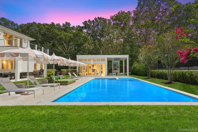 a view of pool with lawn chairs and large trees