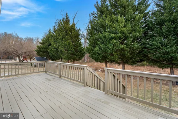 a view of deck with wooden floor and fence and trees in the background