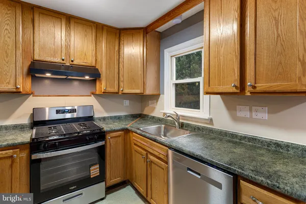 a kitchen with granite countertop stainless steel appliances a stove sink and cabinets
