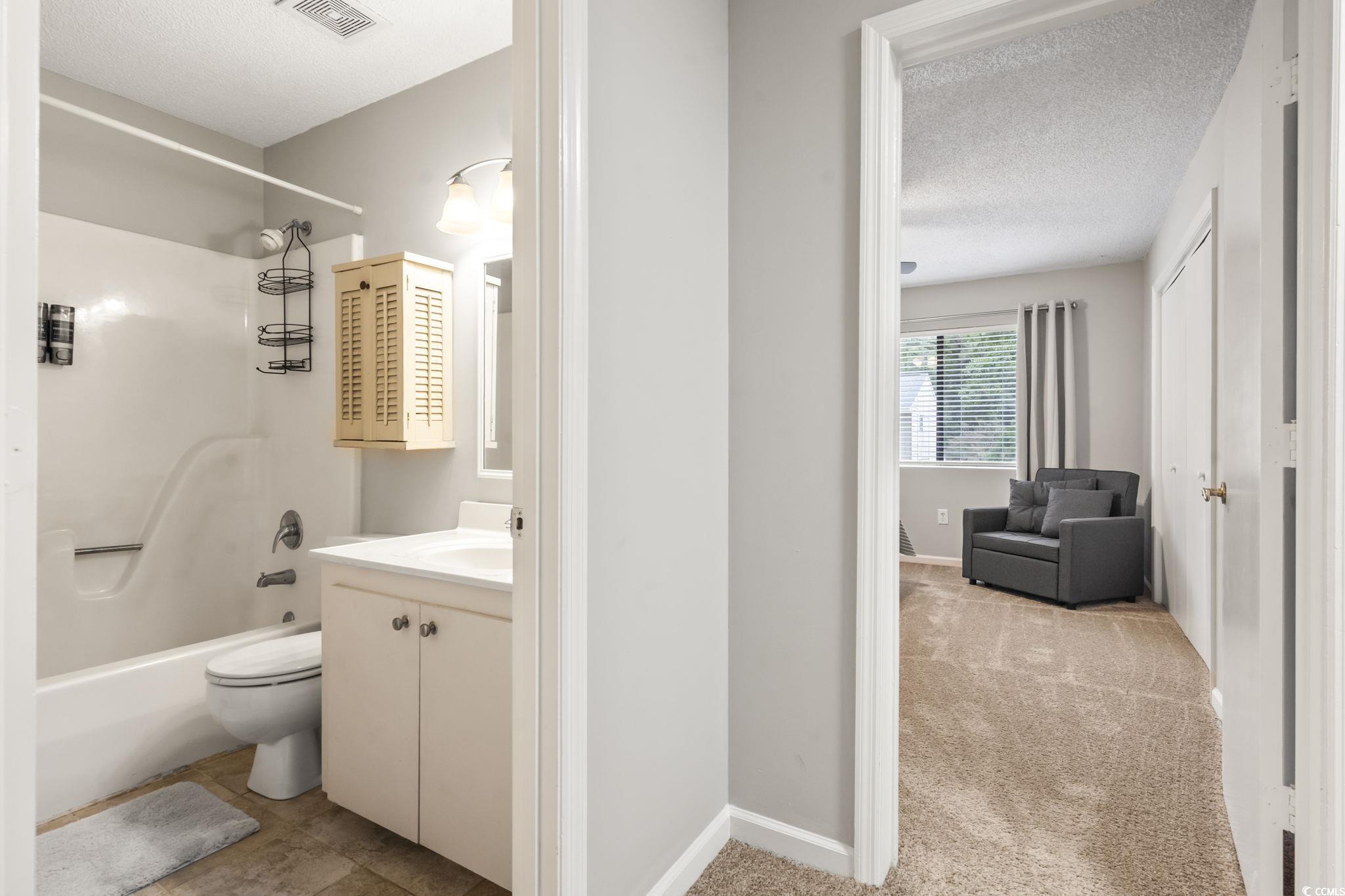 86 Beaver Pond Loop, Unit 33 Pawleys Island, SC 29585 - Photo 17 of 25 Full bathroom featuring vanity, a textured ceiling, light carpet, and shower combination