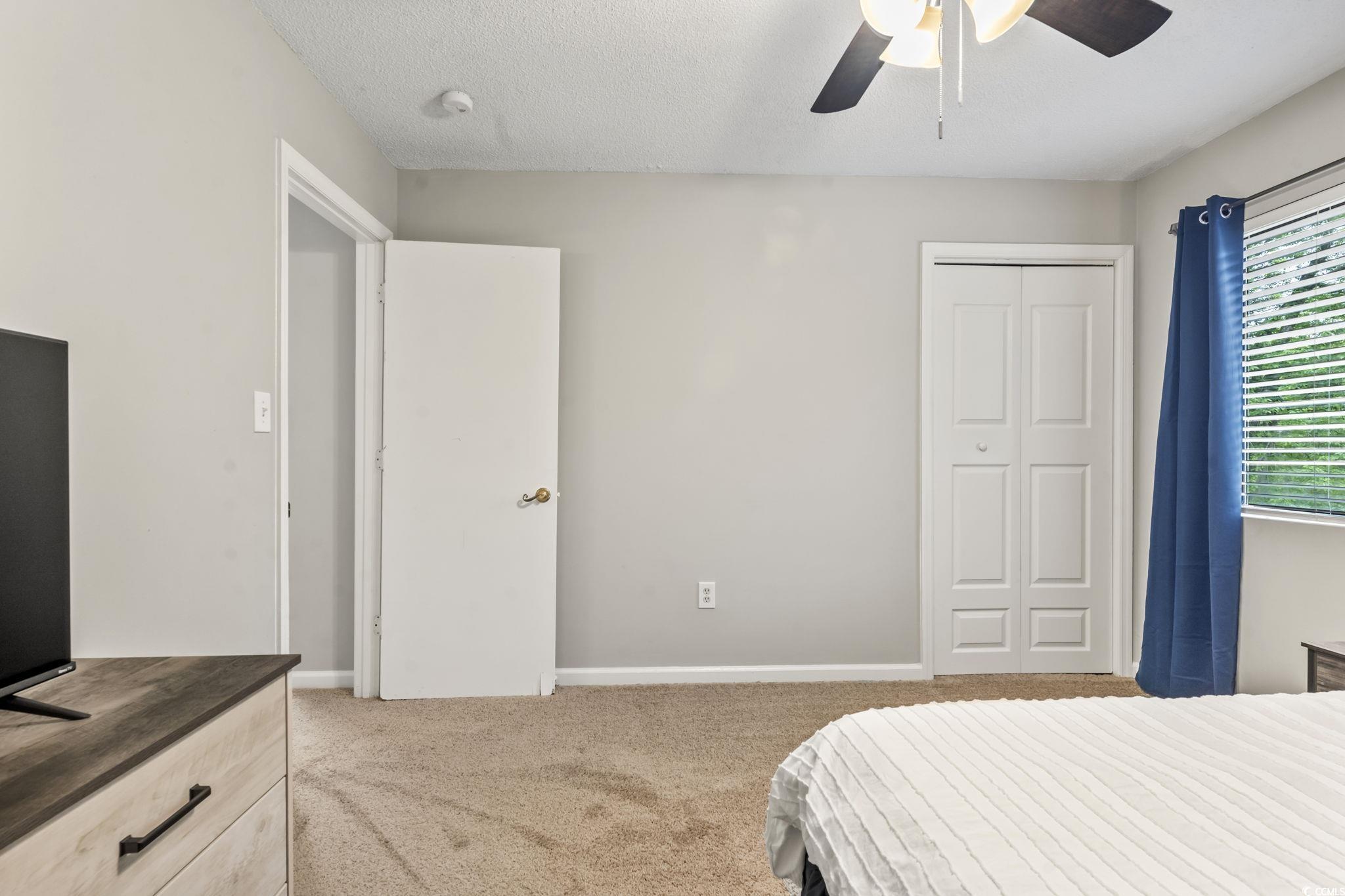 86 Beaver Pond Loop, Unit 33 Pawleys Island, SC 29585 - Photo 19 of 25 Bedroom with light colored carpet, a ceiling fan, a textured ceiling, and a closet