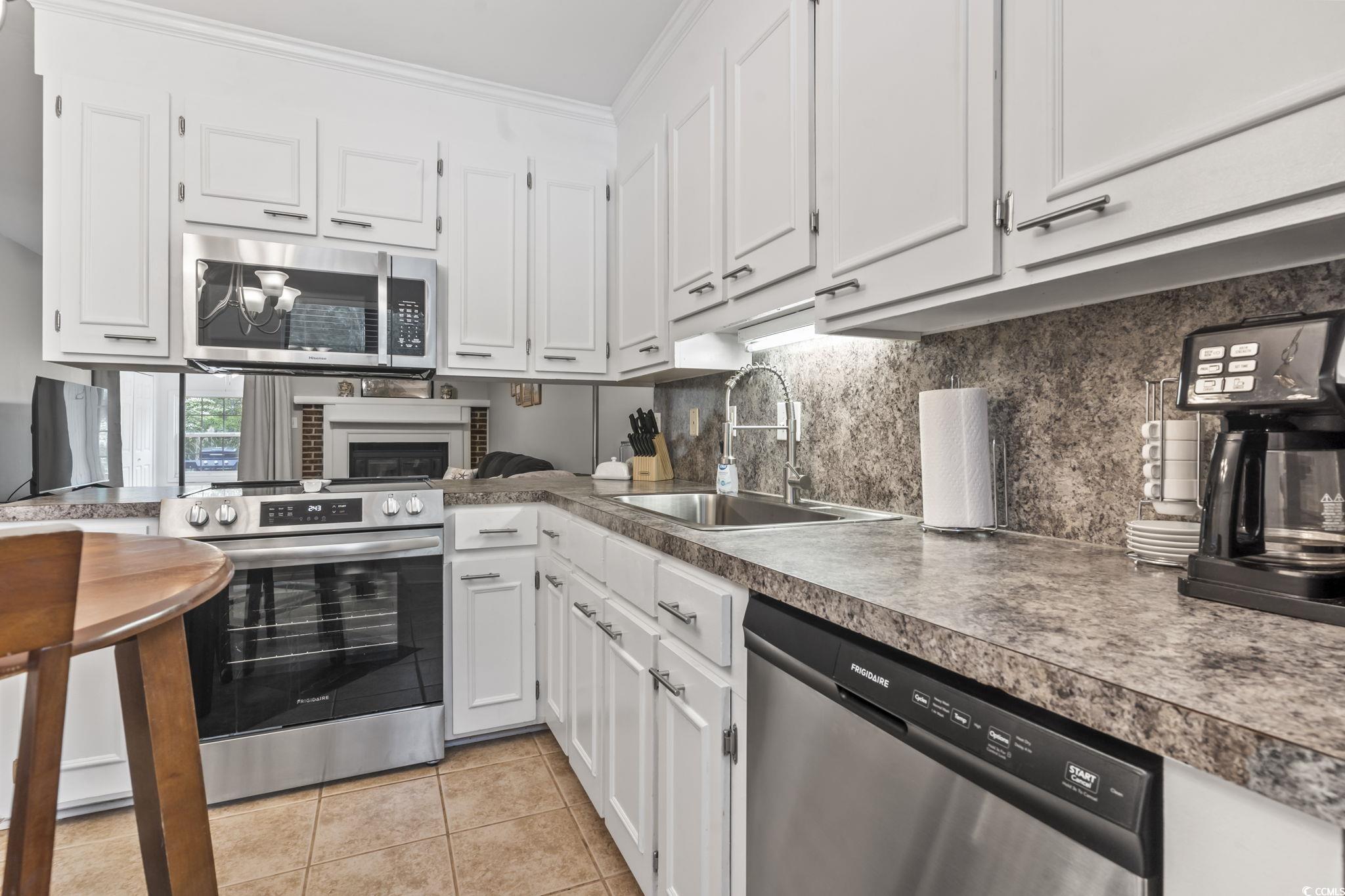86 Beaver Pond Loop, Unit 33 Pawleys Island, SC 29585 - Photo 3 of 25 Kitchen featuring white cabinets, backsplash, appliances with stainless steel finishes, and light tile patterned floors