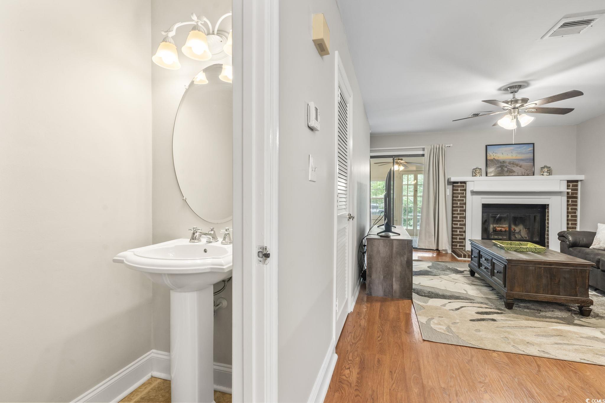 86 Beaver Pond Loop, Unit 33 Pawleys Island, SC 29585 - Photo 6 of 25 Bathroom featuring light wood finished floors, a brick fireplace, and a ceiling fan