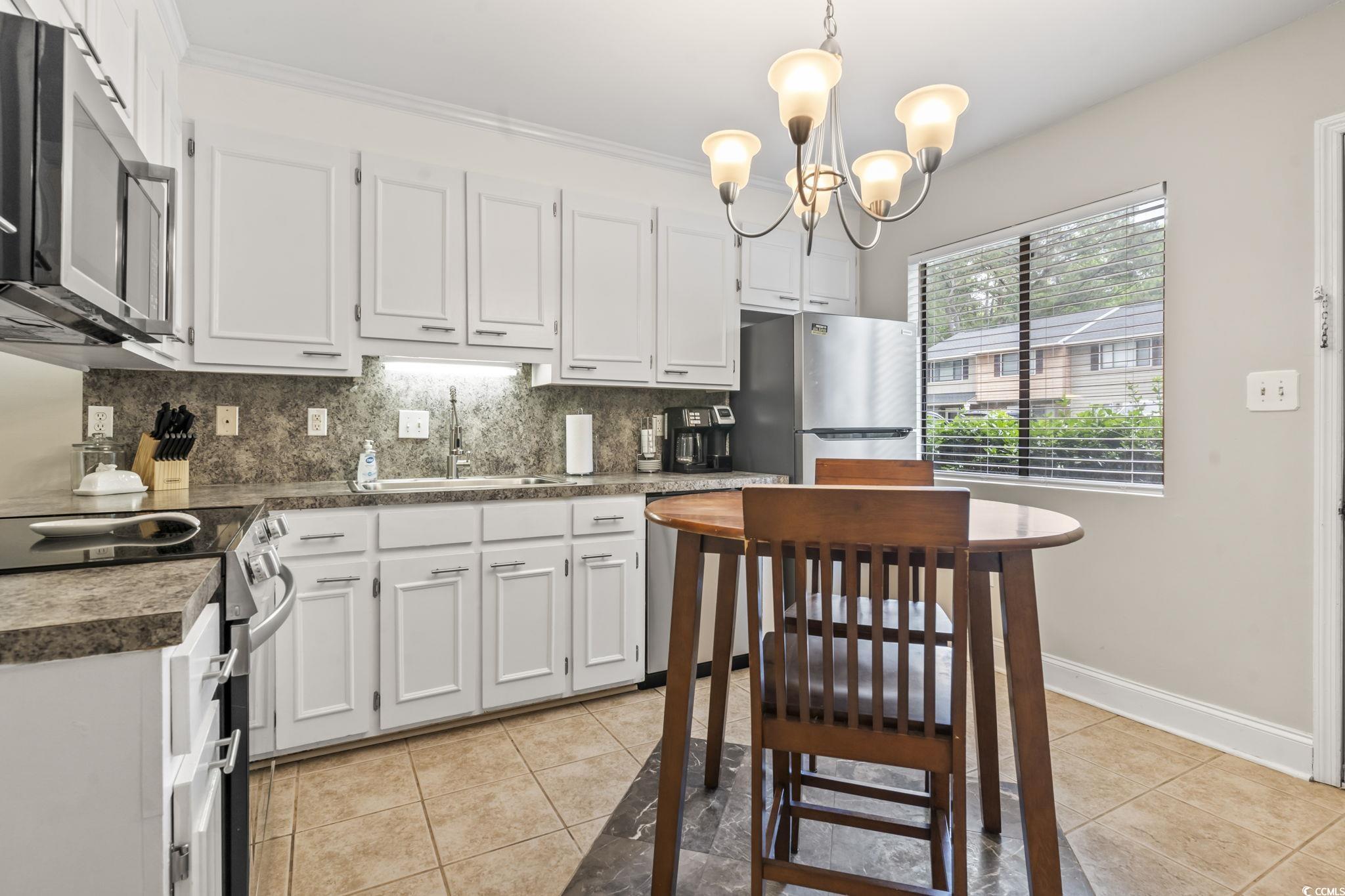 86 Beaver Pond Loop, Unit 33 Pawleys Island, SC 29585 - Photo 7 of 25 Kitchen with decorative backsplash, stainless steel appliances, pendant lighting, white cabinets, and light tile patterned floors