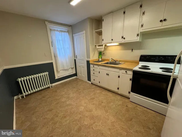 a kitchen with stainless steel appliances granite countertop a stove a sink and white cabinets