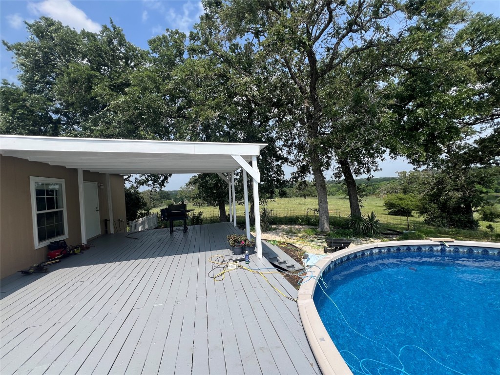 702 Paint Creek Road McDade, TX 78650 - Photo 20 of 40 a view of a patio with table and chairs a barbeque with wooden floor and fence