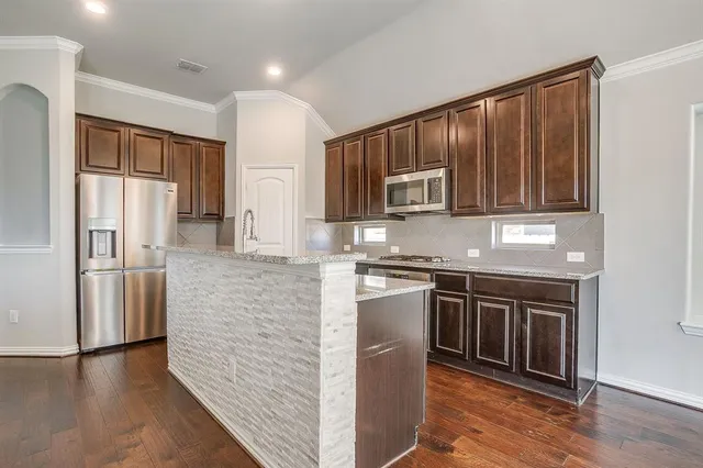 a kitchen with stainless steel appliances granite countertop a sink a stove and a refrigerator