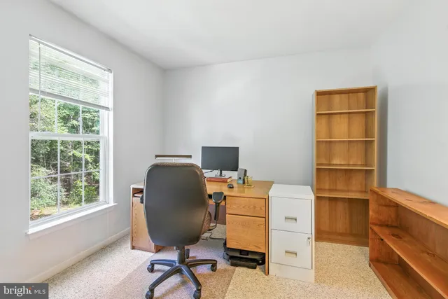 a view of a workspace with furniture and a window