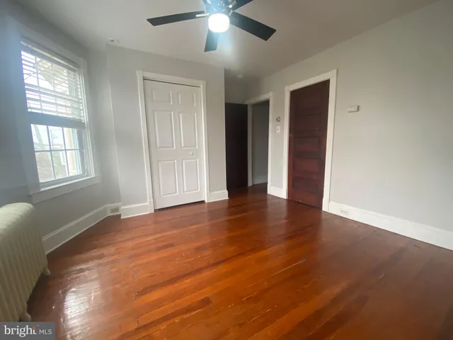 a view of an empty room with window and wooden floor