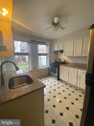 a kitchen with granite countertop a sink a stove a refrigerator a window and cabinets