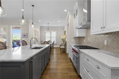 a kitchen with stainless steel appliances granite countertop a sink a stove and a wooden floors