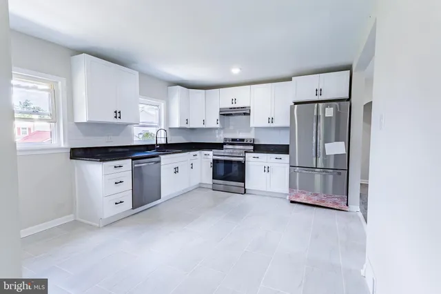 a kitchen with white cabinets stainless steel appliances and a window