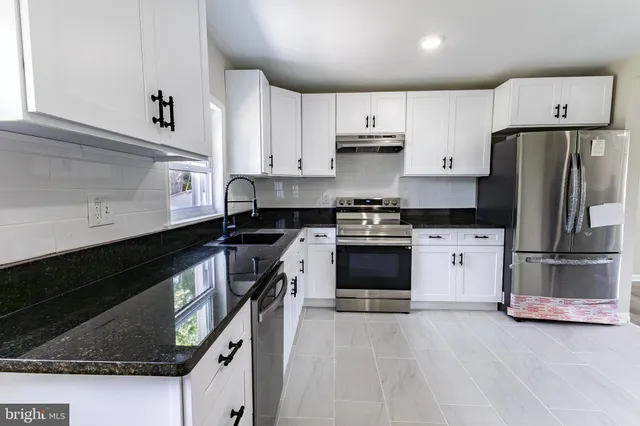 a kitchen with granite countertop white cabinets and stainless steel appliances