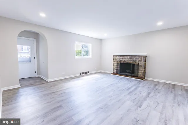wooden floor fireplace and windows in an empty room