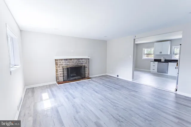 a view of empty room with wooden floor and fireplace