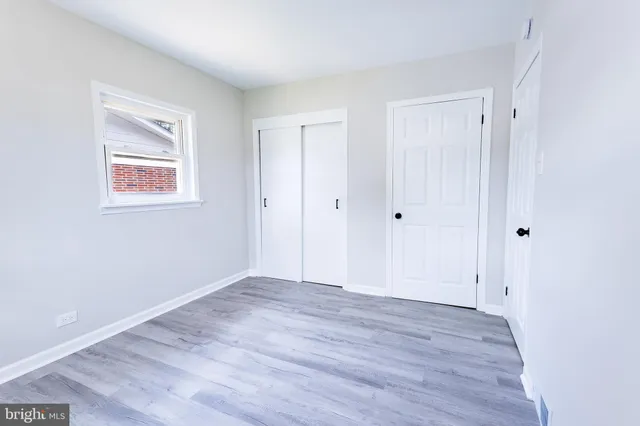 an empty room with wooden floor and window