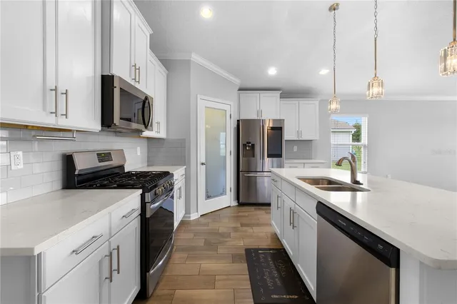 a kitchen with stainless steel appliances a sink stove refrigerator and cabinets
