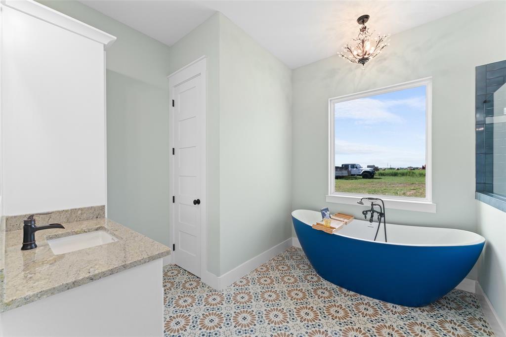 4411 Fm 751 Wills Point Wills Point, TX 75169 - Photo 21 of 40 Freestanding blue soaking tub with floor-mounted faucet, complemented by patterned floor tiles