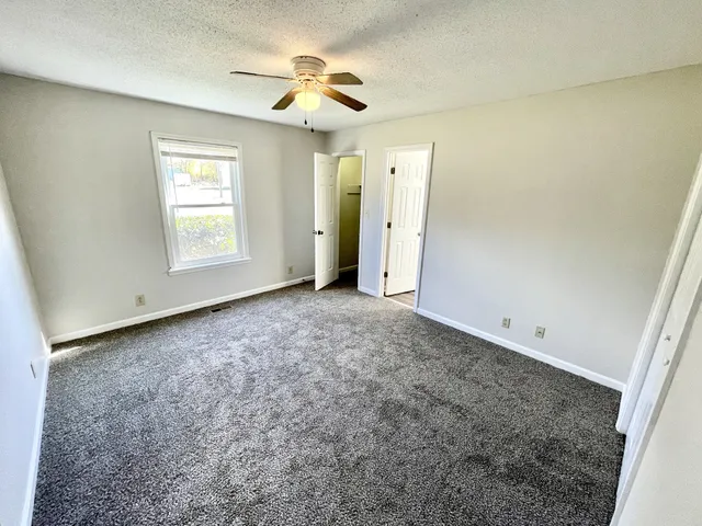 an empty room with a ceiling fan and window