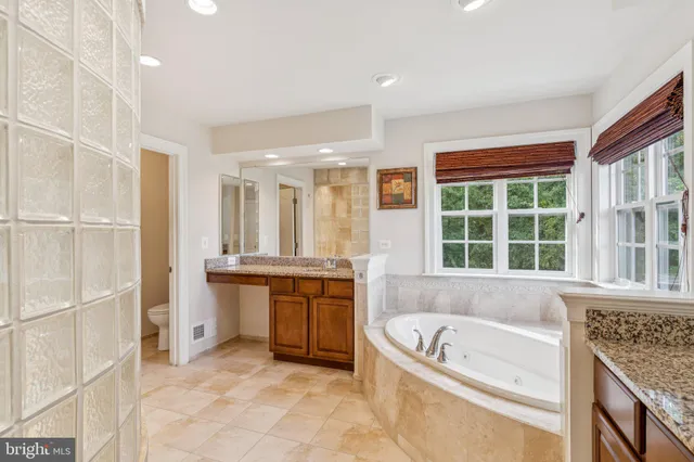 a bathroom with a granite countertop tub a sink and a window