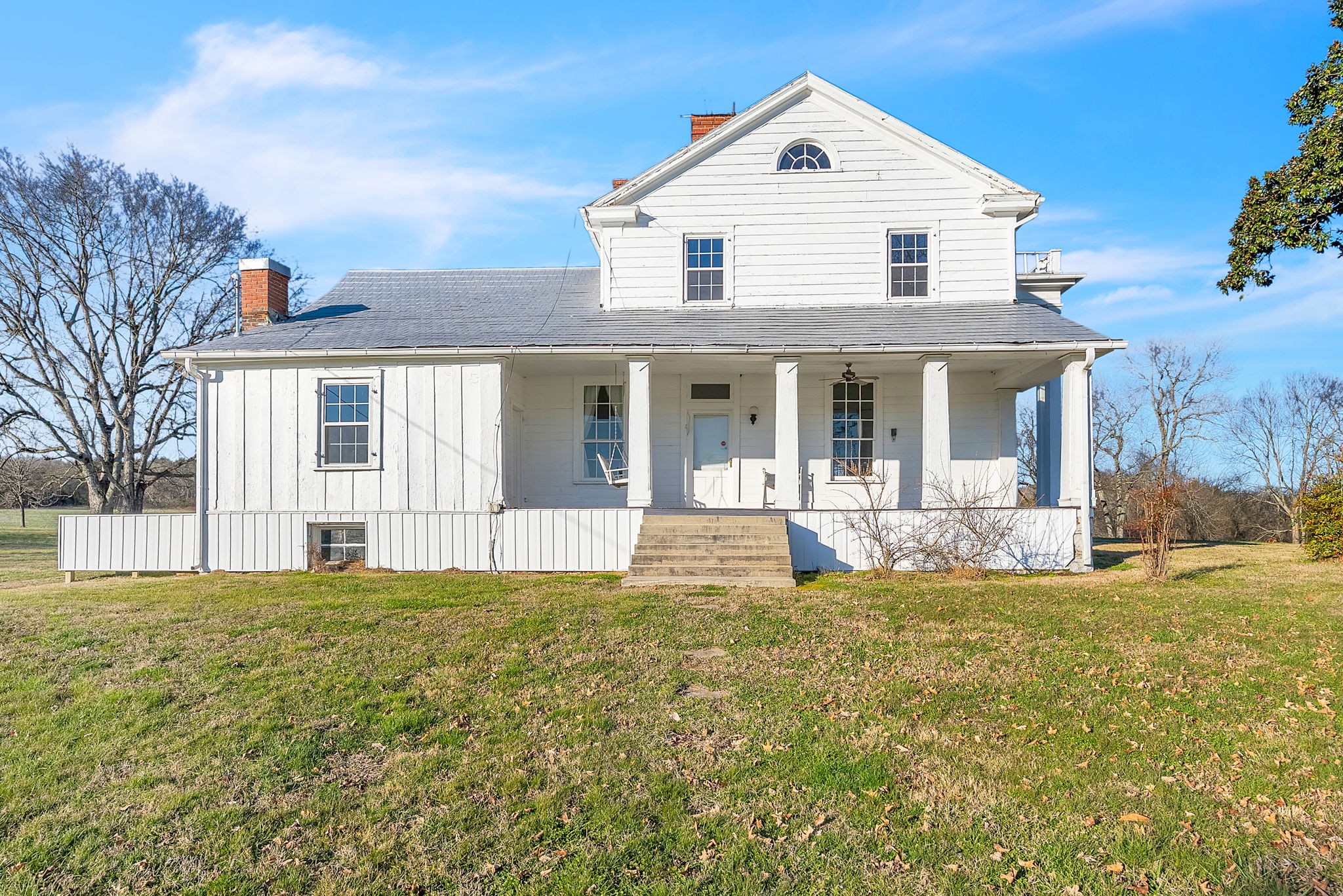 a view of white house with a big yard and large trees