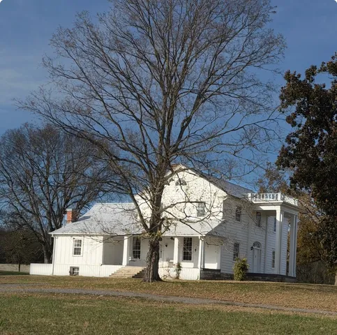 a front view of a house with a large tree
