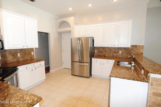 a kitchen with granite countertop a refrigerator and a stove top oven