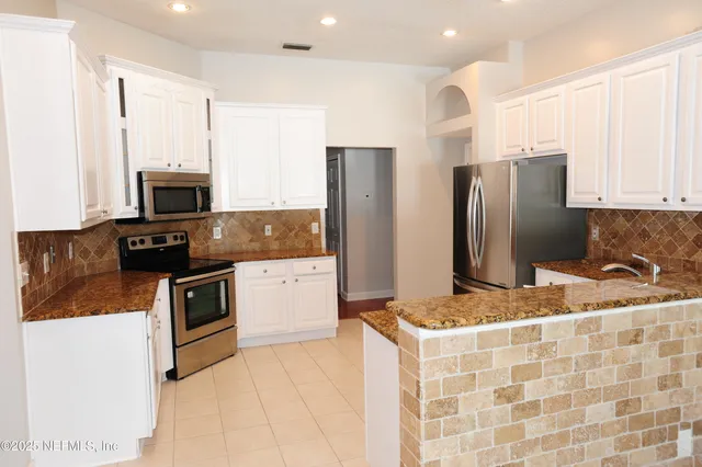 a kitchen with granite countertop a refrigerator and a stove top oven
