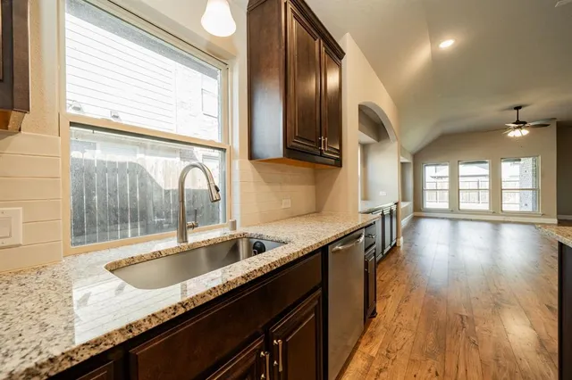 a kitchen with stainless steel appliances granite countertop a sink a stove and a wooden floor