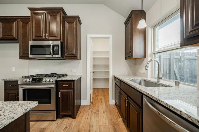 a kitchen with granite countertop a stove sink and cabinets