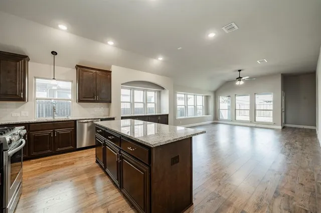 a kitchen with granite countertop a stove top oven sink and cabinets