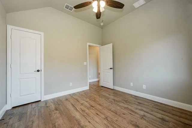 wooden floor in an empty room with a chandelier fan