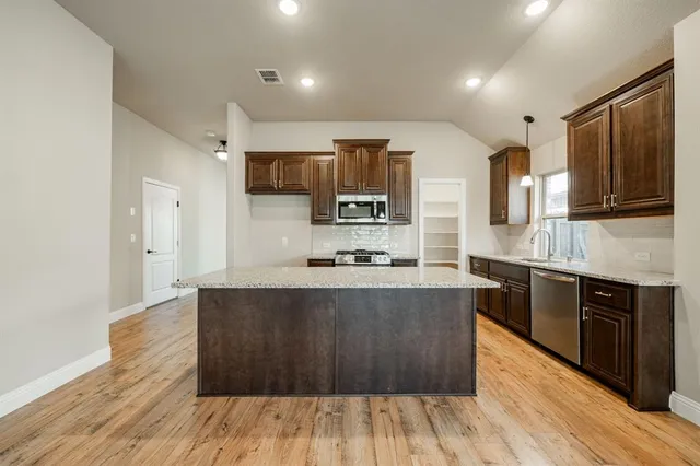a large kitchen with stainless steel appliances wooden floors and wooden cabinets