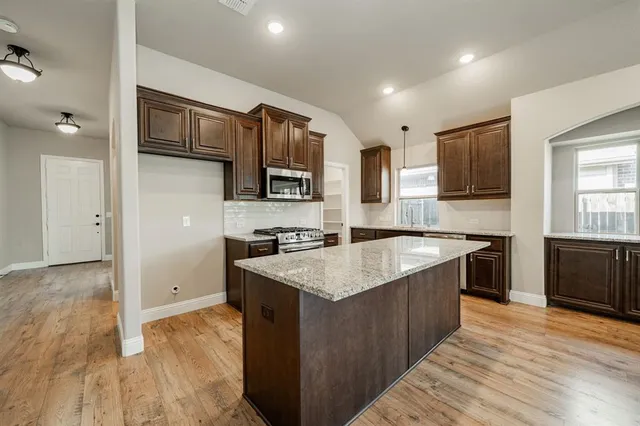 a kitchen with stainless steel appliances granite countertop a sink stove and refrigerator