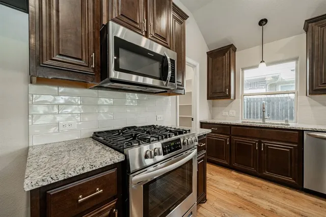 a kitchen with stainless steel appliances granite countertop a stove microwave and sink