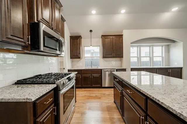 a kitchen with stainless steel appliances granite countertop a sink stove microwave and cabinets